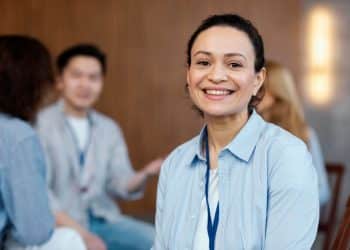 Mulher sorrindo em um ambiente de grupo, representando reflexão e autoconhecimento ao buscar a profissão ideal aos 30 anos.