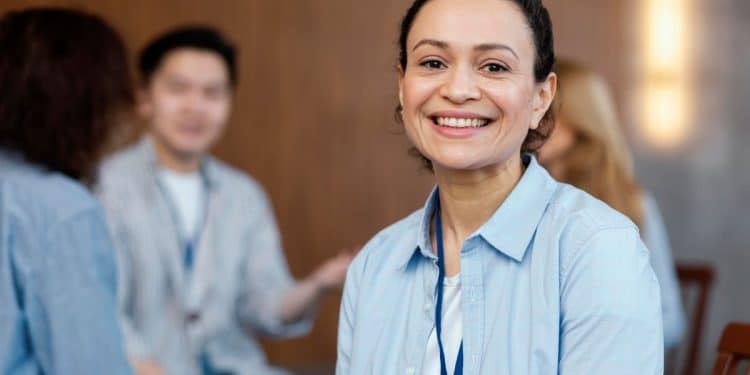 Mulher sorrindo em um ambiente de grupo, representando reflexão e autoconhecimento ao buscar a profissão ideal aos 30 anos.