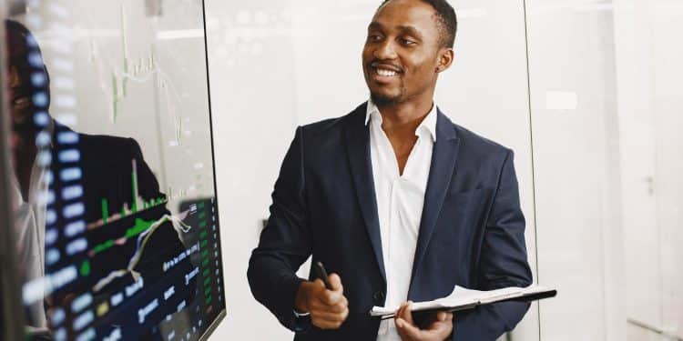 Profissional sorridente fala ao celular enquanto consulta tablet e notebook em escritório moderno