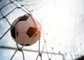 Bola de futebol entrando no gol representando oportunidades de carreira no futebol fora das quatro linhas