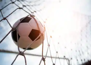 Bola de futebol entrando no gol representando oportunidades de carreira no futebol fora das quatro linhas