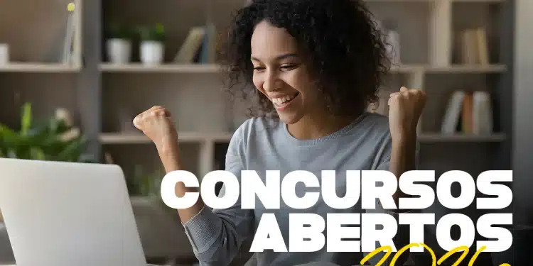 Mulher negra de cabelos cacheados sorri e comemora com os braços levantados em frente a um notebook aberto, com os textos "Concursos Abertos 2026" sobrepostos em branco e amarelo, representando candidatos que podem se inscrever no concurso público da Prefeitura Municipal de Guzolândia — SP, com vagas para Escriturário, Nutricionista Clínico, Médico Pediatra e outros cargos em 2026