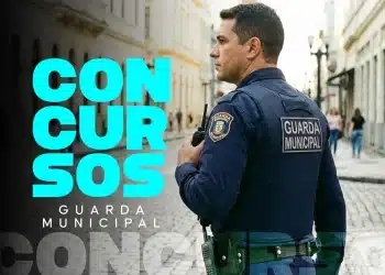 Guarda municipal fardado de azul, de perfil, segurando rádio comunicador em rua histórica de calçamento de pedra, com texto "Concursos Guarda Municipal" em destaque na imagem, representando o concurso público da Prefeitura de Piranhas com 40 vagas