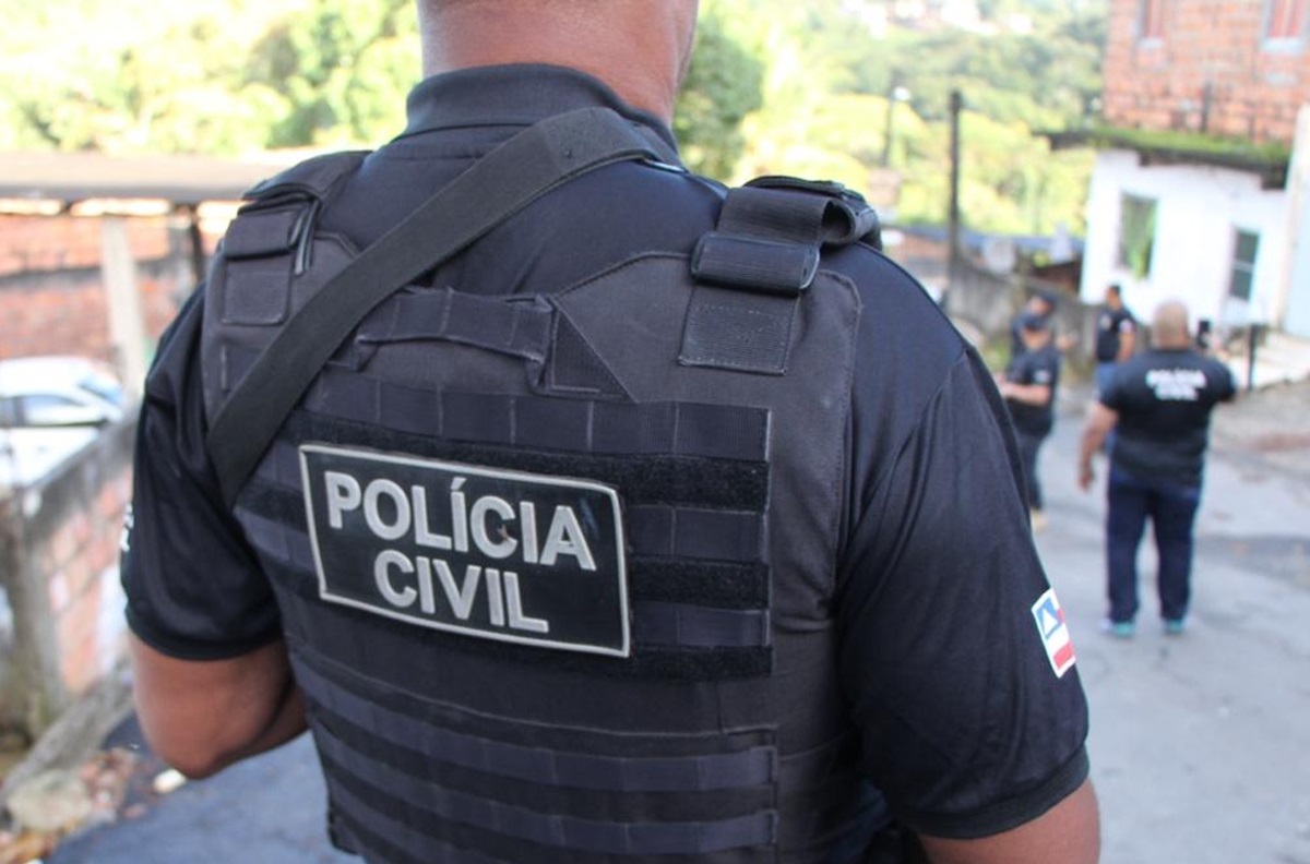 Agente da Polícia Civil da Bahia de costas usando colete tático durante operação em área urbana