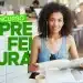 Jovem com fones de ouvido sorridente lendo material de estudo em cafeteria com livros e celular sobre a mesa