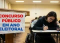 Pessoa escrevendo prova em concurso público durante o ano eleitoral.