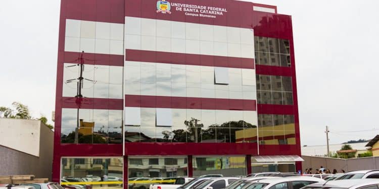 Fachada do campus da Universidade Federal de Santa Catarina em Blumenau, com estacionamento frontal e identificação institucional no topo do prédio