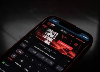 Tela de smartphone exibindo aplicativo de apostas esportivas com odds de futebol, basquete, e-sports e MMA