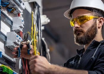 Eletricista trabalhando em quadro de energia, representando uma das profissões menos vulneráveis à inteligência artificial devido ao trabalho manual qualificado.