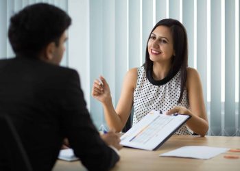 Candidata sorrindo durante entrevista de emprego segurando currículo, representando a importância da autenticidade e consistência entre o que está no currículo e o que é apresentado na entrevista