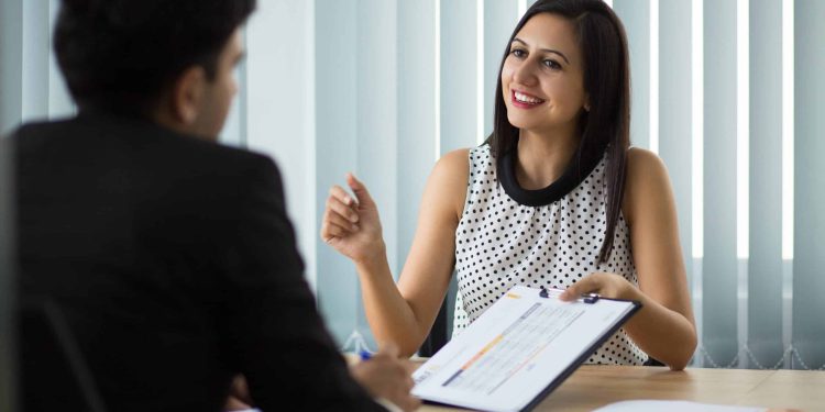 Candidata sorrindo durante entrevista de emprego segurando currículo, representando a importância da autenticidade e consistência entre o que está no currículo e o que é apresentado na entrevista
