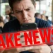 Homem olhando para celular com expressão de dúvida, com a palavra 'FAKE NEWS!' sobreposta, em um café. Tema relacionado a desinformação sobre mudanças no imposto de renda 2026.