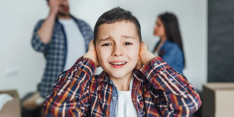 Criança cobrindo os ouvidos, visivelmente angustiada enquanto os pais discutem em segundo plano.