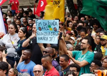 Manifestação com trabalhadores segurando cartaz pedindo fim da escala 6x1 e redução da jornada de trabalho no Brasil.