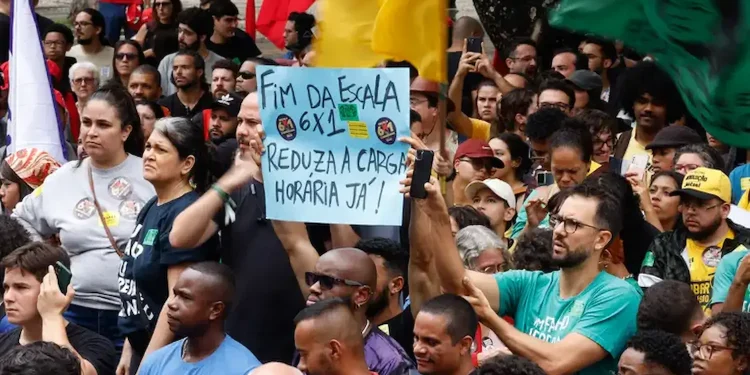 Manifestação com trabalhadores segurando cartaz pedindo fim da escala 6x1 e redução da jornada de trabalho no Brasil.