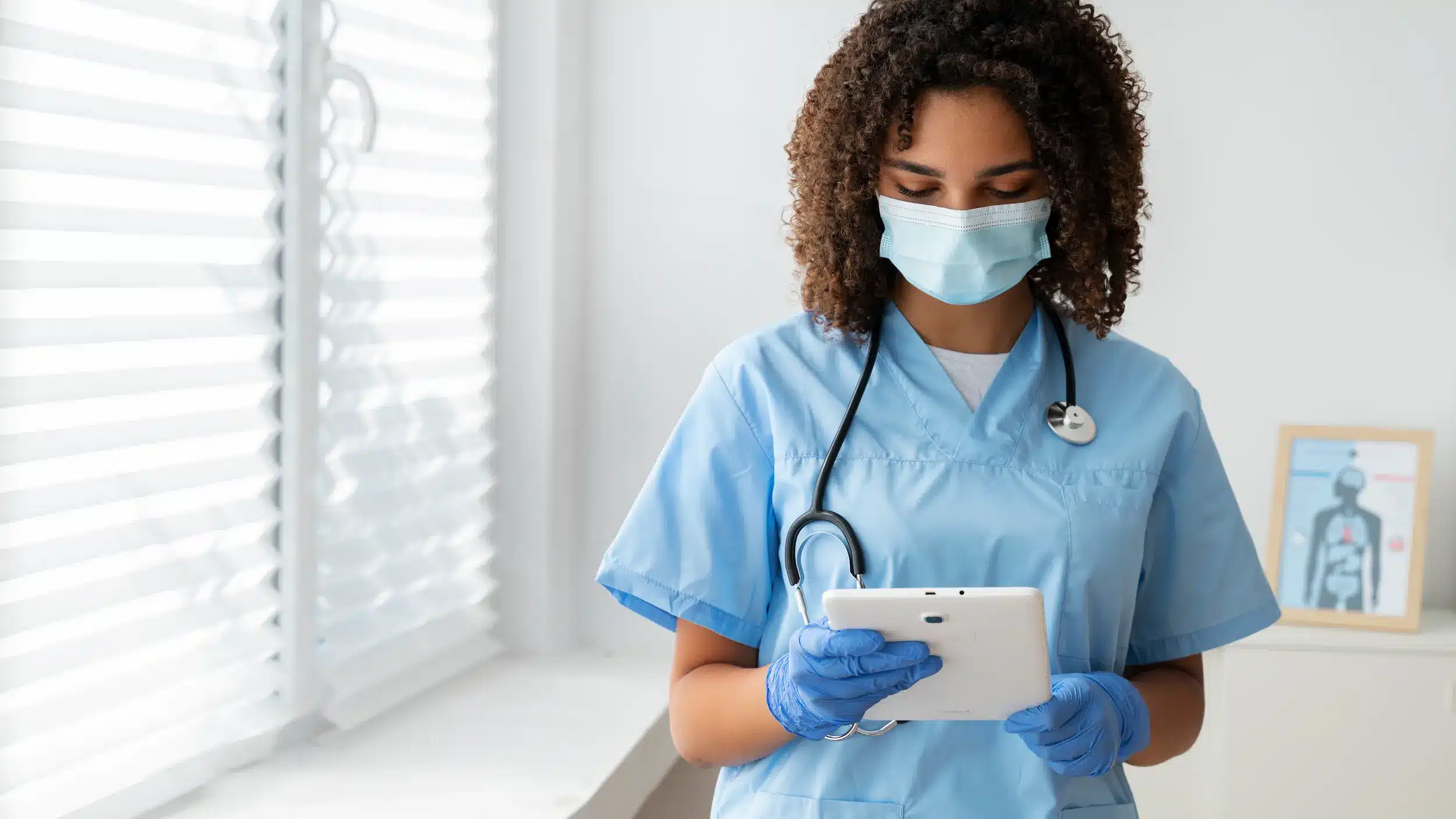Profissional de saúde utilizando tablet em ambiente clínico durante rotina.