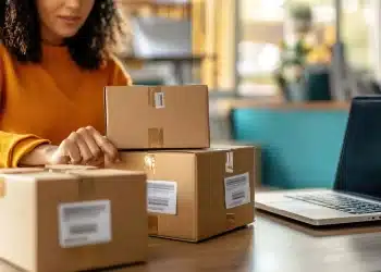 Mulher organizando pacotes de compras em uma mesa, representando a proposta do governo sobre a eliminação da taxa das blusinhas.