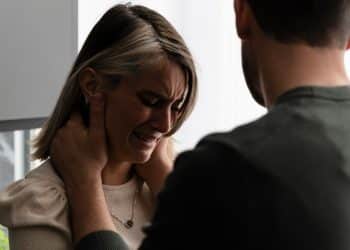 Mulher jovem chorando enquanto homem aponta o dedo em sua direção em ambiente doméstico, demonstrando sofrimento emocional em um relacionamento com pessoa narcisista.