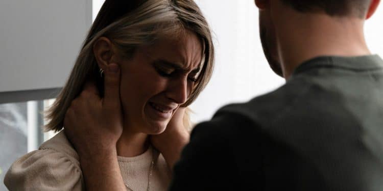 Mulher jovem chorando enquanto homem aponta o dedo em sua direção em ambiente doméstico, demonstrando sofrimento emocional em um relacionamento com pessoa narcisista.