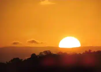 pôr do sol quente, simbolizando os dias de verão, com a dúvida sobre o retorno do horário de verão em 2026.