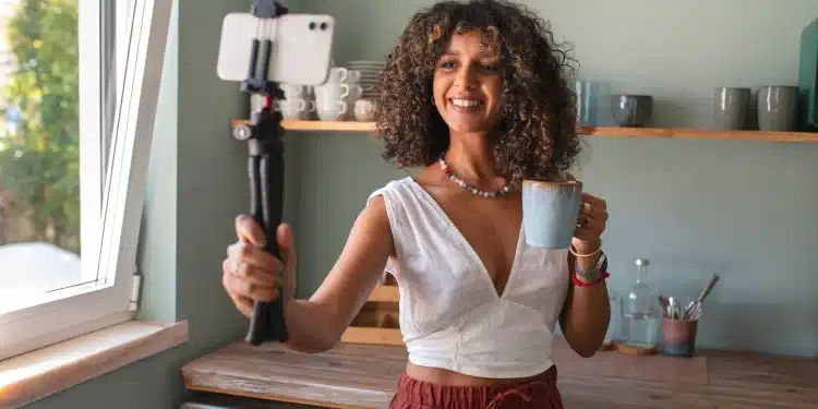 Influenciadora sorrindo enquanto tira uma selfie com um copo de café, representando a rotina e estilo de vida dos influenciadores digitais no Brasil.