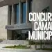 Fachada de prédio público com letreiro "Câmara Municipal" e bandeira do Brasil hasteada, com texto sobreposto destacando a abertura de concurso