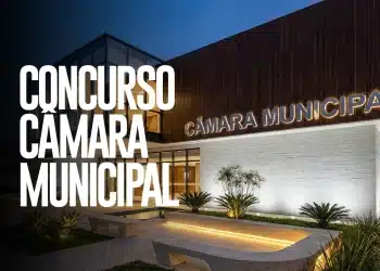 Fachada iluminada da Câmara Municipal em período noturno com jardim ornamental e bancos de concreto em primeiro plano