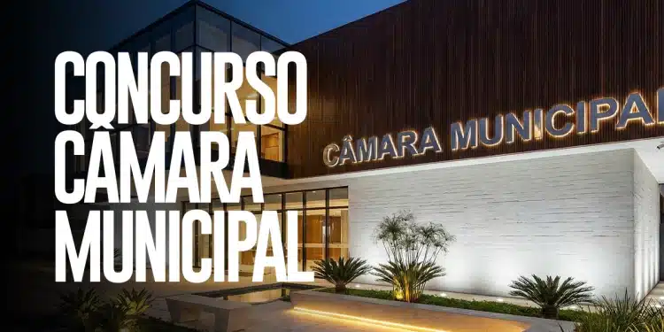 Fachada iluminada da Câmara Municipal em período noturno com jardim ornamental e bancos de concreto em primeiro plano