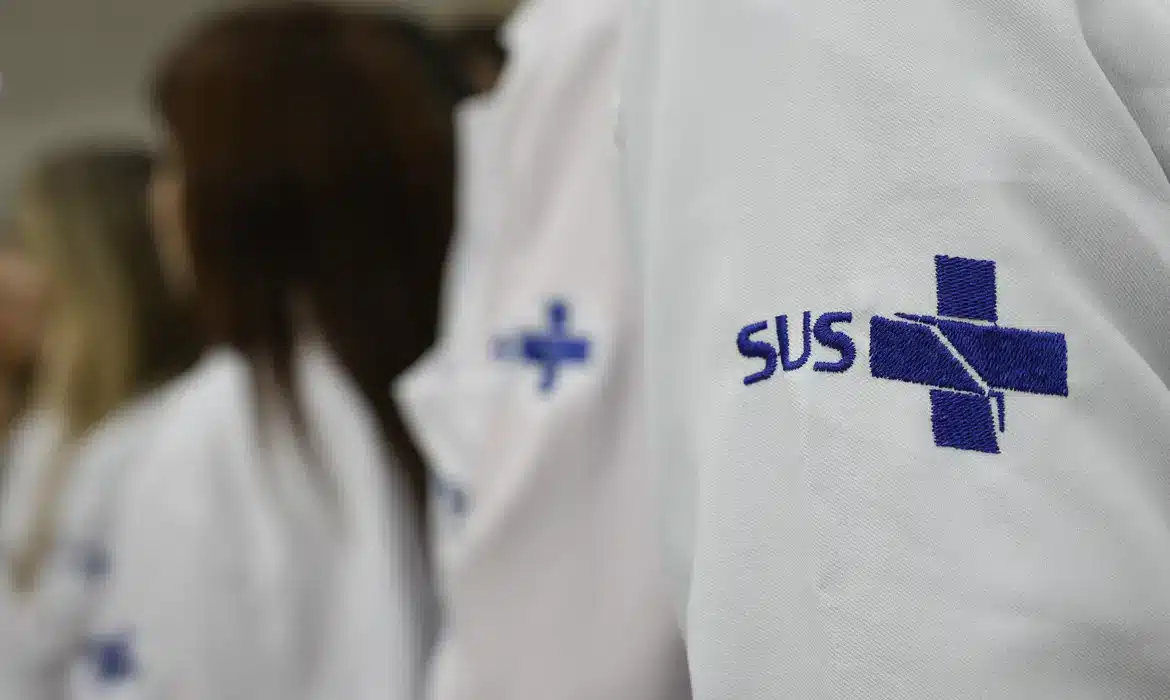 Jaleco branco com o logo do SUS bordado, representando os médicos que atuam pelo programa Mais Médicos para o Brasil em regiões prioritárias do sistema público de saúde