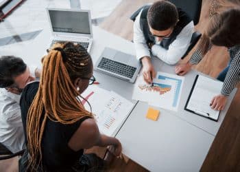 Grupo de profissionais em reunião de trabalho discutindo gráficos e dados sobre a transformação do mundo do trabalho.