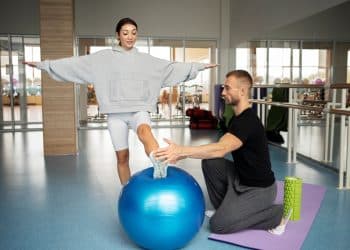 Profissional de Educação Física auxiliando paciente em processo de reabilitação física, destacando as diversas áreas de atuação na área.