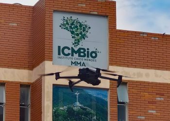 Fachada do Instituto Chico Mendes de Conservação da Biodiversidade com drone em voo, representando as atividades de monitoramento e gestão ambiental desempenhadas pelos agentes temporários do ICMBio.