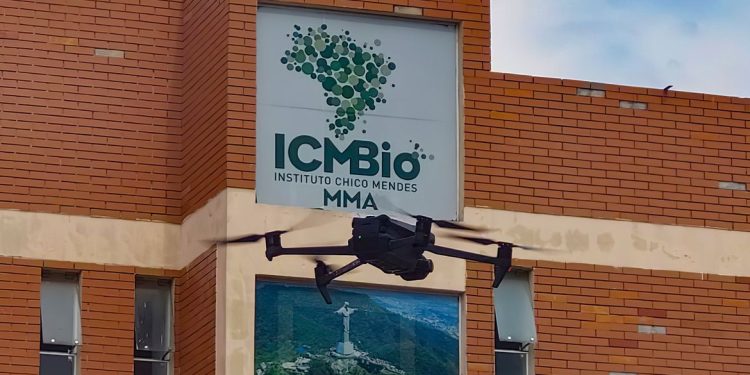 Fachada do Instituto Chico Mendes de Conservação da Biodiversidade com drone em voo, representando as atividades de monitoramento e gestão ambiental desempenhadas pelos agentes temporários do ICMBio.