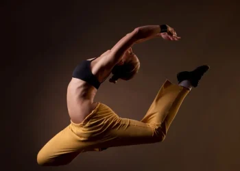 Dançarina executa salto artístico com flexibilidade e força, representando a valorização profissional após regulamentação da profissão de dançarino