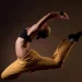 Dançarina executa salto artístico com flexibilidade e força, representando a valorização profissional após regulamentação da profissão de dançarino