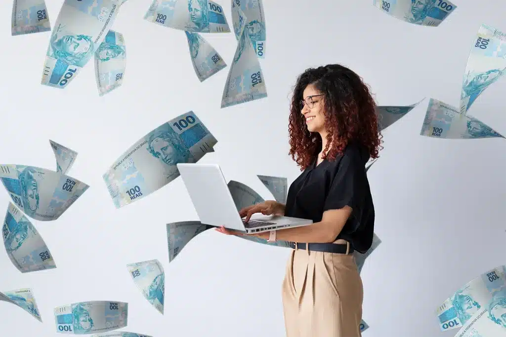 Profissional trabalhando no notebook com dinheiro ao redor simbolizando profissões acessíveis e lucrativas em 2026