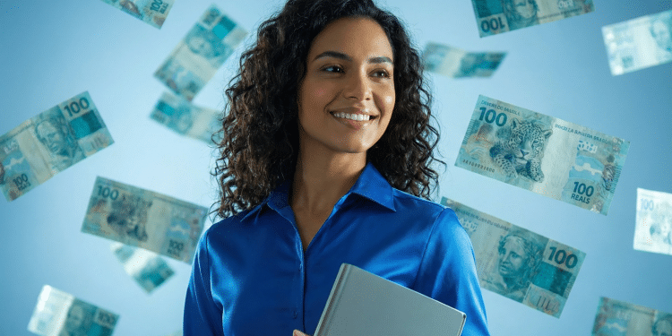 Mulher de cabelos cacheados e camisa azul segura notebook enquanto notas de 100 reais flutuam ao redor