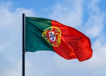 Bandeira de Portugal tremulando no céu azul representando oportunidades profissionais e salários em 2026.