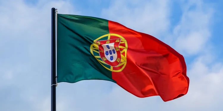 Bandeira de Portugal tremulando no céu azul representando oportunidades profissionais e salários em 2026.