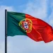Bandeira de Portugal tremulando no céu azul representando oportunidades profissionais e salários em 2026.