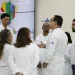 Grupo de médicos com jalecos brancos do SUS conversando em frente ao painel do programa Mais Médicos para o Brasil, representando os profissionais selecionados para atuar em regiões prioritárias do SUS