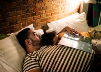 Casal adormecendo juntos na cama, ilustrando como o contato próximo pode induzir o sono devido à sensação de segurança e carinho.