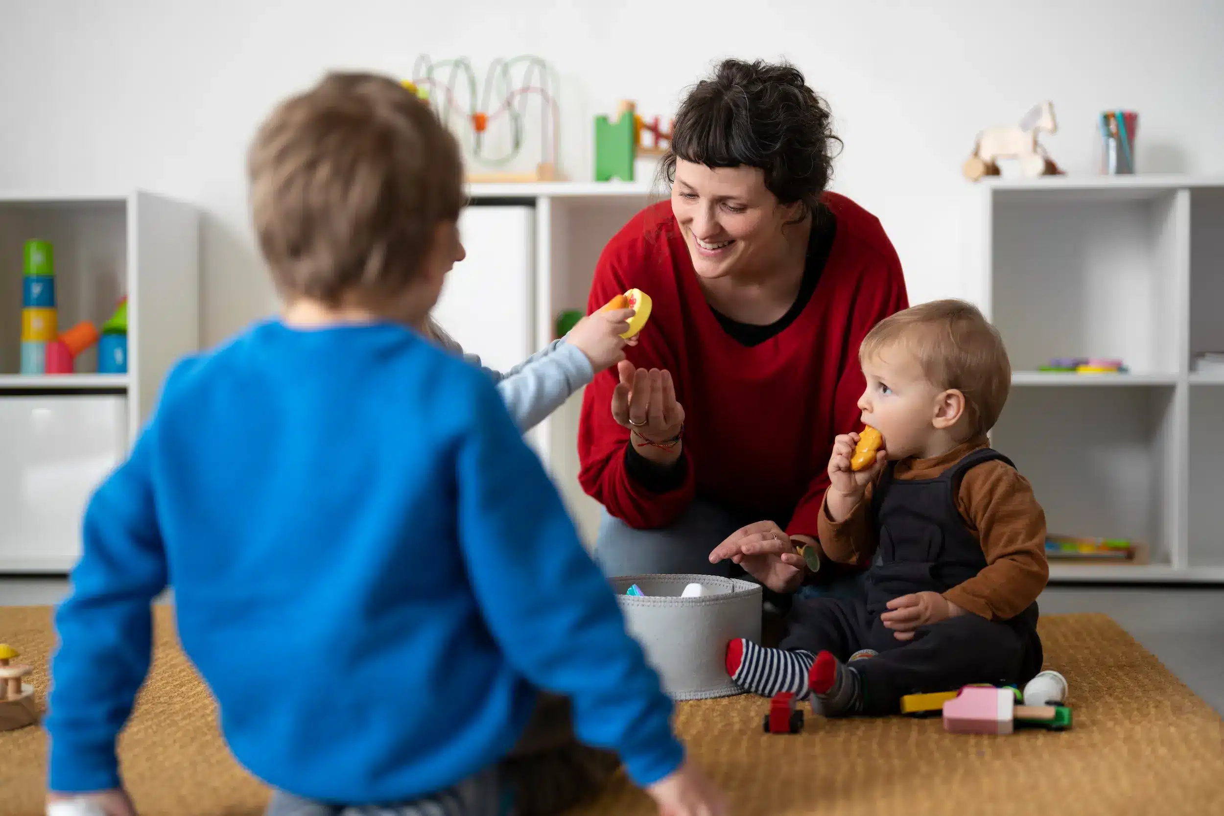Mulher cuidando de duas crianças pequenas em ambiente doméstico, representando famílias com filhos de até 5 anos elegíveis ao auxílio-creche.