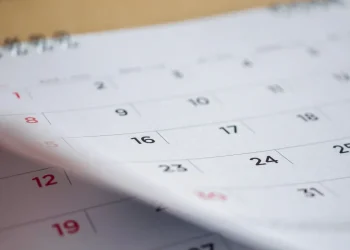 Calendário impresso em destaque, representando as regras da CLT sobre feriados nacionais e o pagamento em dobro para quem trabalha em datas comemorativas