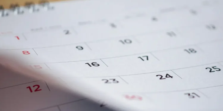 Calendário impresso em destaque, representando as regras da CLT sobre feriados nacionais e o pagamento em dobro para quem trabalha em datas comemorativas