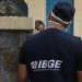 Agente do IBGE de costas, com colete de identificação do instituto, em frente a uma residência, representando o trabalho de campo realizado pelos candidatos aprovados no processo seletivo simplificado do IBGE