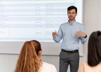 Professor universitário ministrando aula enquanto explica conteúdos e formação necessária para atuar na carreira acadêmica.