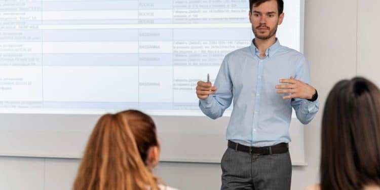 Professor universitário ministrando aula enquanto explica conteúdos e formação necessária para atuar na carreira acadêmica.