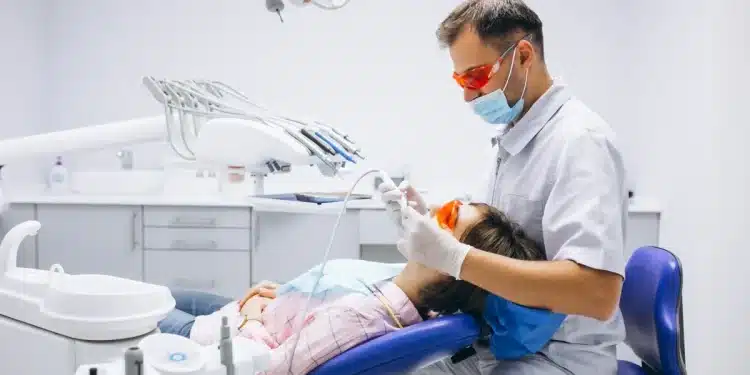 Dentista realizando procedimento odontológico em paciente mulher em consultório