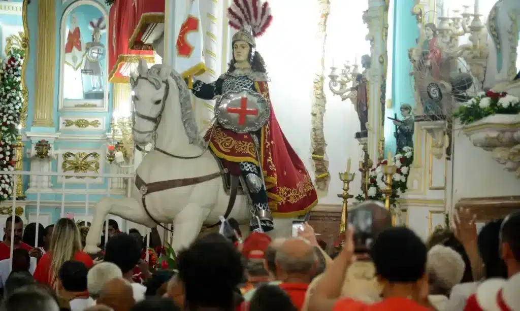 São Jorge em sua estátua, montado em um cavalo, durante celebração religiosa, simbolizando sua proteção e coragem.